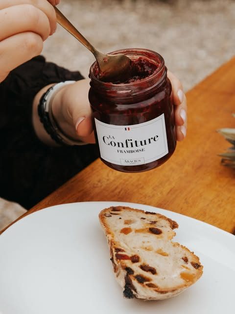 Pot de confiture de framboise maison et tranche de pain aux fruits secs