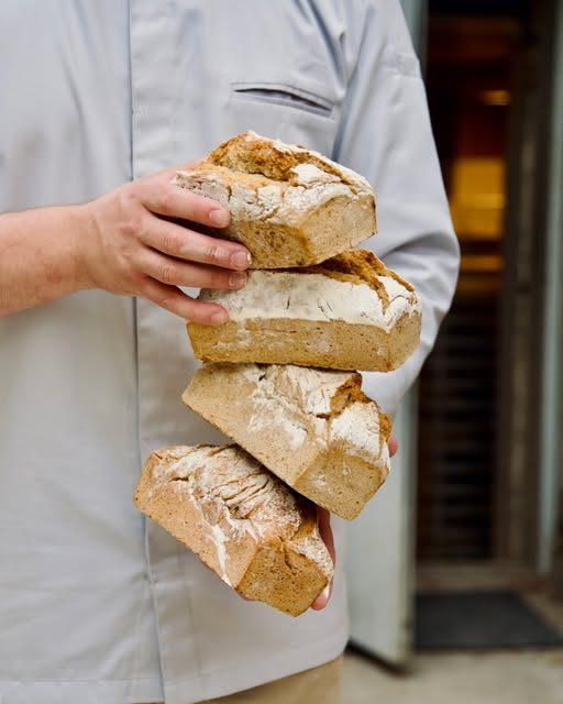Boulanger portant quatre pains de campagne farinés