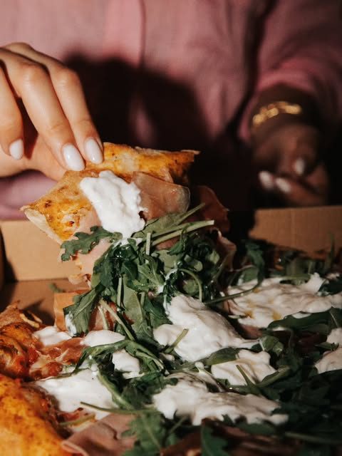 Part de pizza blanche garnie de burrata, jambon cru et roquette